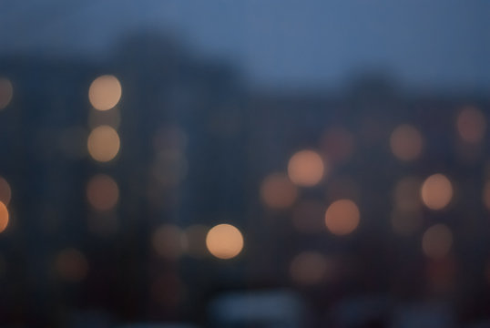 Blurred background of evening cityscape with luminous windows
