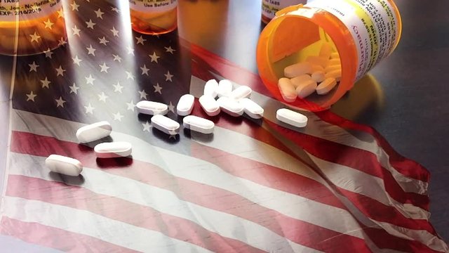 4k Slow Motion Medicine Bottles and Pills Falling With Ghosted American Flag Waving. The medicine bottle labels are non-proprietary with fictitious names, addresses and information designed specifical