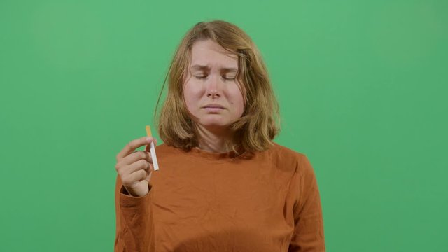 Woman Taking The Cigarette Out Of The Mouth With Disgust Suggesting The Bad Influence Of Tobacco. Studio Isolated Shot Against Green Screen Background