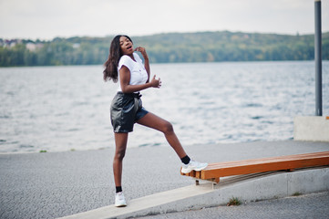 African american dark skinned slim model posed in a black leather shorts and white t-shirt.