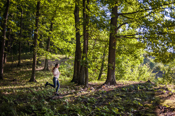 Young girl jogging in the woods on a sunny morning.