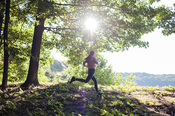 Young girl jogging in the woods on a sunny morning.