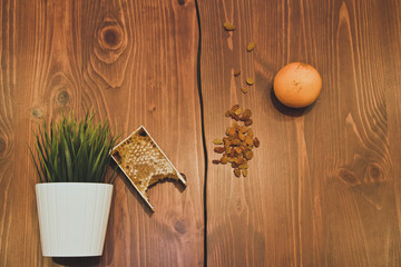 honey in combs next to raisins with green grass leaves on a wooden background