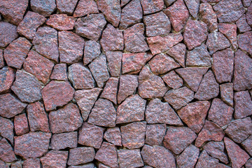 an old wall of bright red marble stones of various shapes and sizes. rough surface texture