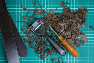 belt on a cutting mat with pieces of leather and a cutting tool. handmade craft