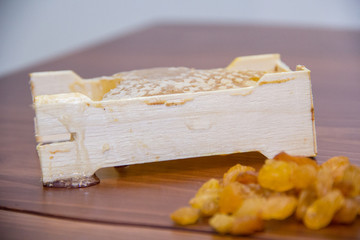 honey in honeycomb next to raisins on a wooden background