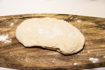 Fototapeta na wymiar dough with flour on a wooden background