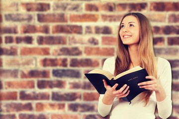 Man holding old bible book on brick wall background
