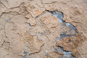 old beige gray heavily damaged concrete wall with cracks and peeling paint. rough surface texture