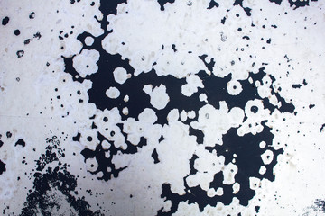 shabby dark black spots of paint on a white gray wall with scratches. rough surface texture