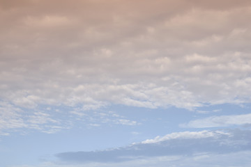 Obraz premium The clouds. The light of the sun through the clouds against a bright sky at sunset. Clouds on the blue sky. Sunset.