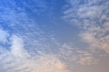 The clouds. The light of the sun through the clouds against a bright sky at sunset. Clouds on the blue sky. Sunset.