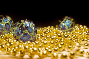 Christmas toys with the beads on the table a black background. Gold beads with blue balls. Christmas decorations with shiny patterns.