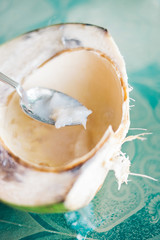 Coconut cut open in half with silver spoon scooping out fresh fruit
