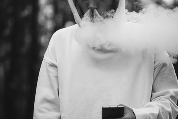 A man exhales a cloud of steam black and white photo. Vaping and health problems
