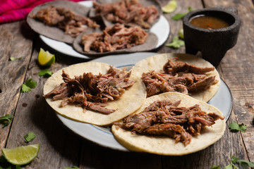 Mexican slow cooked lamb tacos also called barbacoa on wooden background