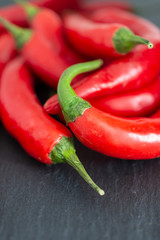 Top view of a close-up of chillies on black slate background, with unfocused background