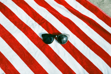 Pair of sunglasses on red and white striped beach towel