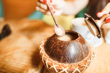 Original coconut sugar bowl. White sugar in a wooden spoon.