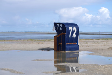 Blauer Strandkorb am Wattenmeer und Wasserlachen am Strand - Stockfoto