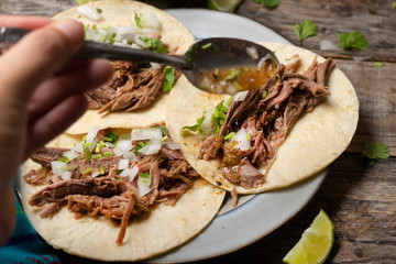 Mexican slow cooked lamb tacos also called barbacoa on wooden background