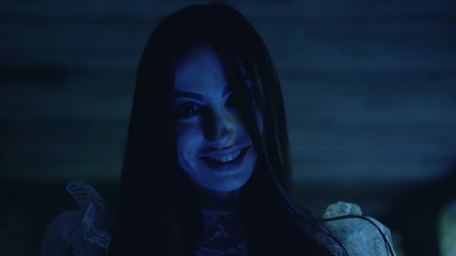 Insane smile on crazy maniac woman face, mysterious hair-raising atmosphere