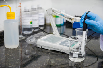 Woman hands performing pH test on pH meter electronic instrument
