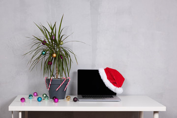 Christmas palm tree with ornaments. Office desk laptop