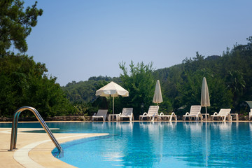White umbrellas and sun loungers by the pool