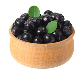 Chokeberry in wooden bowl isolated on white background. Black aronia