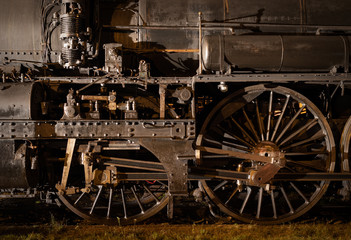 Fototapeta na wymiar Historic steam locomotive, close up of wheels and rods illuminated at night