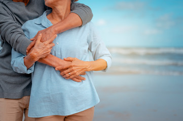 Senior couples embrace on the beach at sunny day, plan life insurance with the concept of happy...