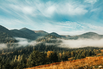 Fototapeta na wymiar Aerial view amazing over of the Carpathian Mountains or Carpathians with Beautiful autumn landscape , sunrise, blue sky with white clouds, fog between the mountain slopes