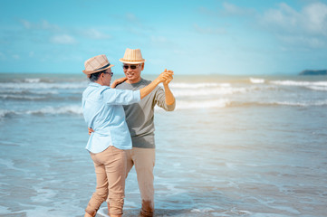 Senior couple dancing on the beach on good days, plan life insurance at retirement concept.