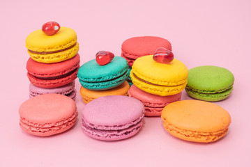 Fototapeta na wymiar A lot of french colorful macarons on a pink background