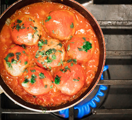 Iron pan with raw cutlets on a gas stove