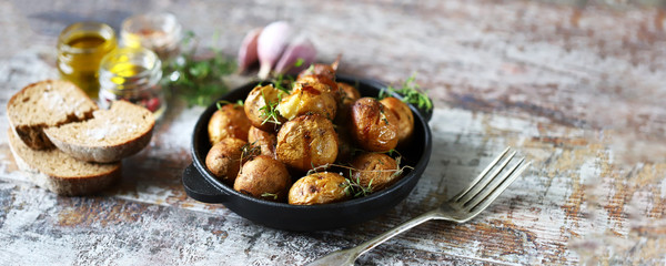 Rustic baked potatoes in a pan with herbs. Selective focus. Macro.