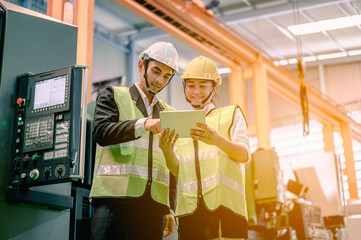 Male and female industrial engineers wearing helmets are using laptops to study and talk about new projects  and professionally. Engineering and architecture technology for factory industry concept.