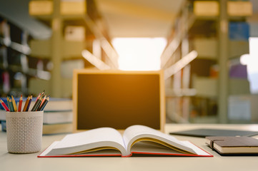 Opened book with pencil box and blackboard on the desk wood in the library prepare for new knowledge.  Education background concept.