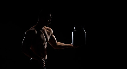 Model sports young man on dark background. Portrait of sporty strong muscle guy with protein drink in shaker. Sexy torso. Bodybuilding nutrition supplements, sport, workout, healthy lifestyle concept.