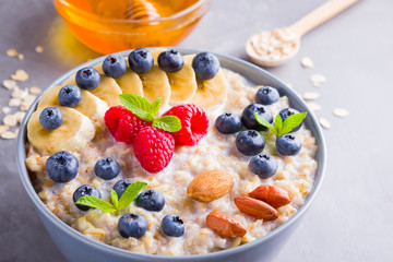 Oatmeal with berries and nuts for breakfast. Oatmeal with fruits, nuts and honey. Oatmeal with blueberries, banana and raspberries. Healthy food