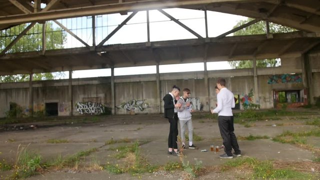 Smiling teenagers drinking beer outside and smoking cigarettes. Alcoholism concept. Full shot.