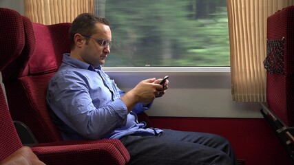 Young man in the train looking on the mobile phone, sending messages