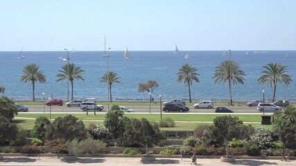 Sail boats on sea, cars on highway and pedestrians on sidewalk, in Mallorca
