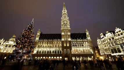 Fototapeten Christmas tree and city hall of Brussels by night, people walk in Grand Place © MEDIAIMAG