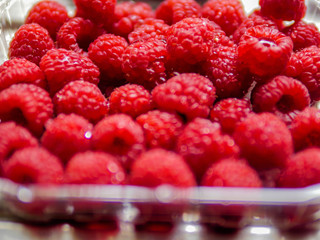 Red fresh juicy raspberry in a plastic packaging, Close up. Selective focus, Concept fresh fruit, healthy eating, organic produce.