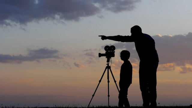 Father teach son how to photo the sunset with camera on tripod