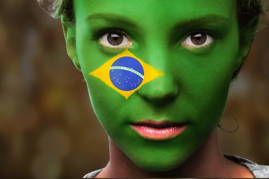 Portrait of a woman with the flag of the Brazil painted on her face