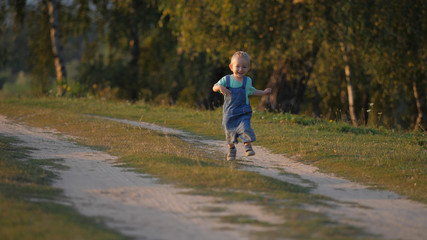 Fototapeta premium Happy baby child running on rural road, smiling kid speeding to embrace life