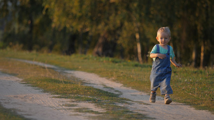 Lovely baby child running on dusty countryside road, kid enjoying life